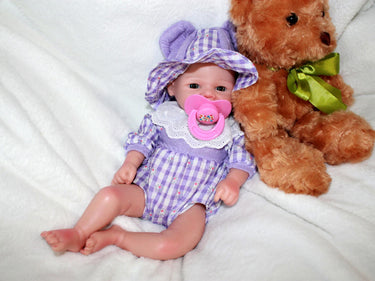 A teddy bear sits beside a doll, both positioned on a soft surface, creating a cozy playtime scene.